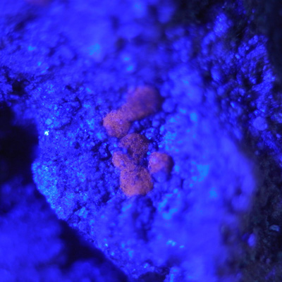 43 UV - Aragonite (?) under ultraviolet light - 3 x 3 mm.